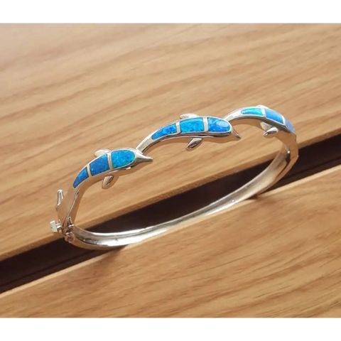 Silver dolphin bangle bracelet with vibrant blue opal inlays, protection symbol