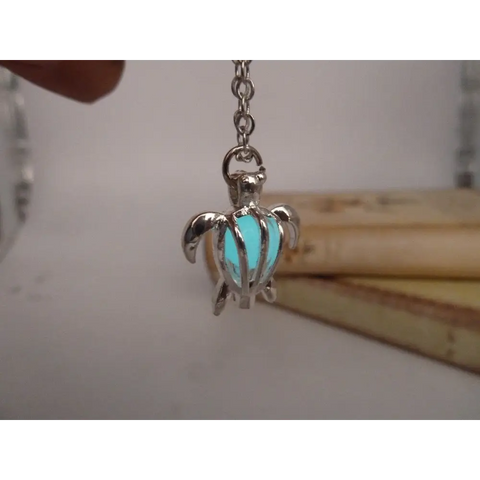 Silver turtle pendant with glowing turquoise interior on chain, symbol of protection