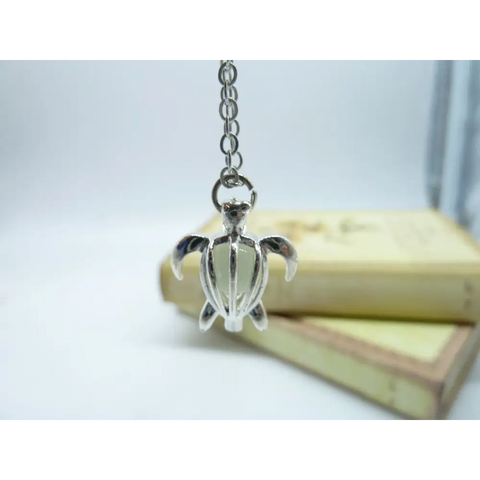 Silver turtle pendant necklace with light-green interior on chain, symbol of protection