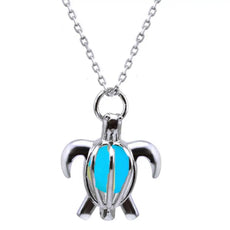 Silver turtle pendant necklace with glowing turquoise interior, symbol of protection